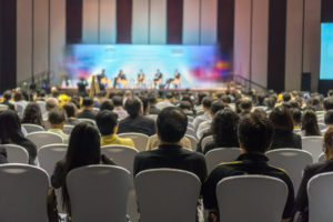 rear-view-audience-listening-speakers-stage-conference-hall-seminar-meeting-scaled
