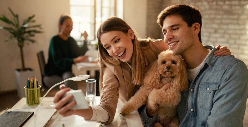men, woman and dog looking at a phone in a shared office